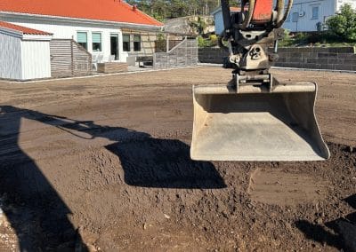 Grävare som jämnar till marken med grävmaskin